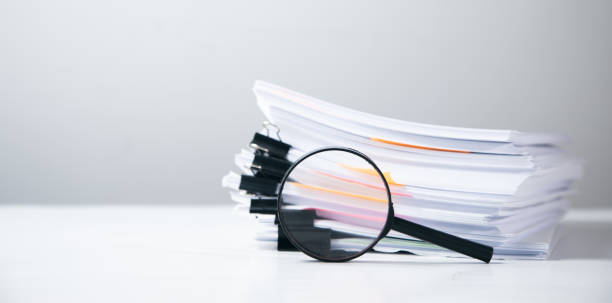 istock Stack of report paper documents with magnifying glass. 1351294460