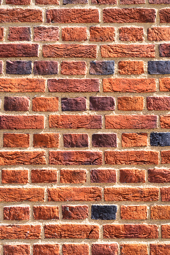 A large surface of recently built brick wall, with a variety of brick colours producing a patterned texture.
