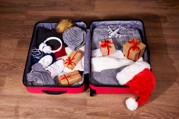 istock Packing luggage, preparing things for a trip for Christmas. A suitcase with warm clothes, passport, Santa Claus hat, gifts and accessories for New Year and Christmas holidays, travel 1351297539