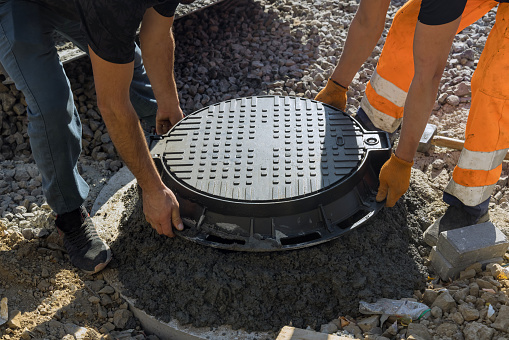 Un trabajador instala una arqueta de alcantarillado en un tanque séptico hecho de anillos de concreto photo