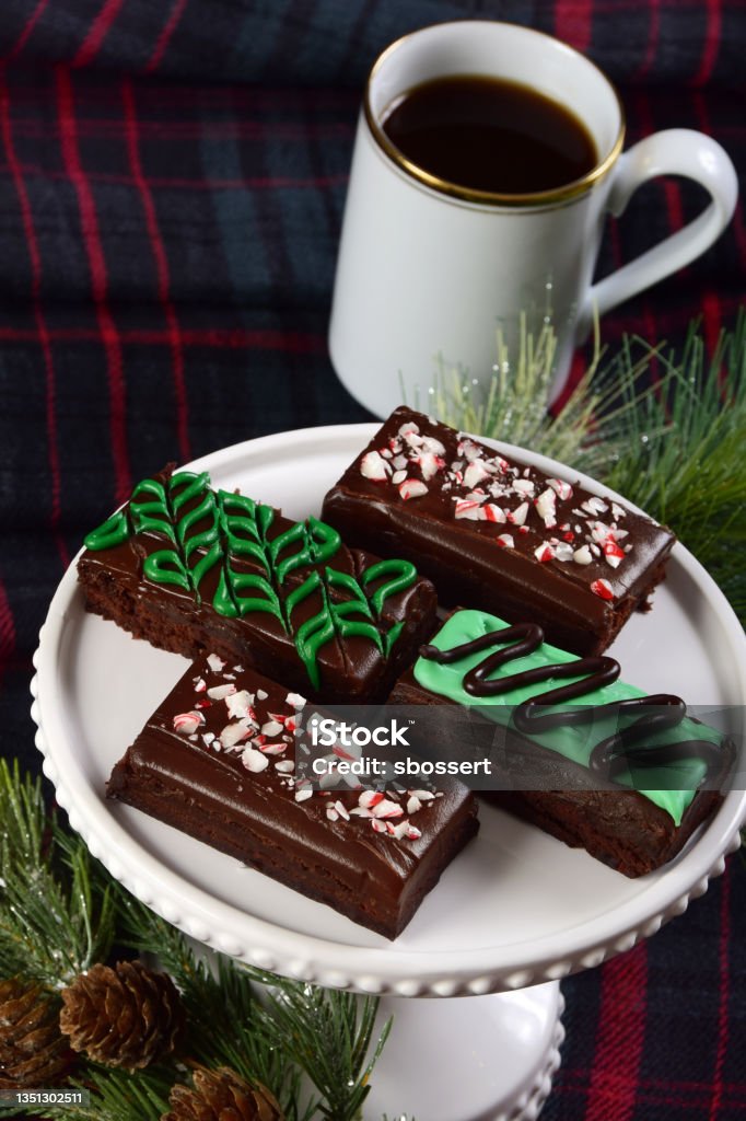 Holiday Mint Chocolate Fudge Brownies A selection of mint chocolate fudge brownies decorated for Christmas with icing and crushed candy cane surrounded by festive pine boughs. Baked Stock Photo