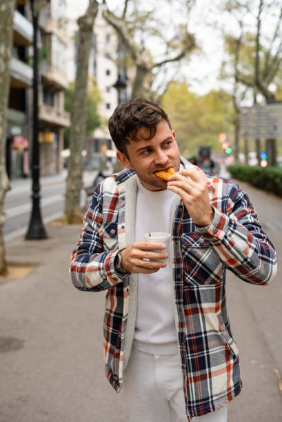 istock Glad man eating sweet churros in city 1351302521