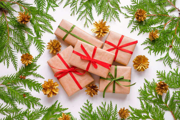 Group of Christmas presents wrapped in kraft paper surrounded of thuja branches on white background. stock photo