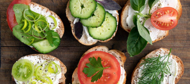 istock banner with various vegetable sandwiches with cream cheese, tomatoes, dill, cucumbers, leeks and basil. serving a vegetarian sandwiches for appetizers on cutting board. top view 1351306742