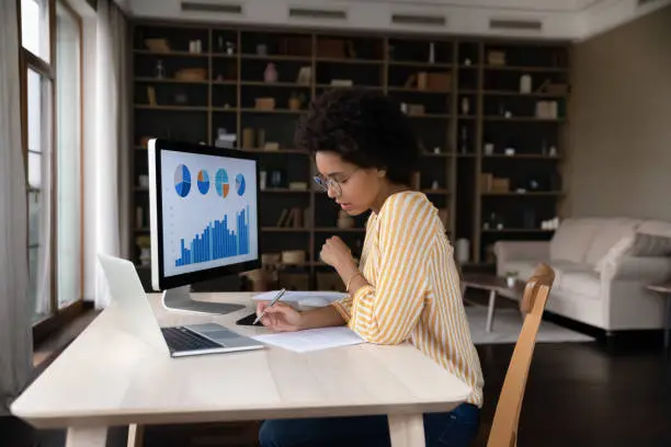 Photo of Concentrated young african american woman working with economic report.