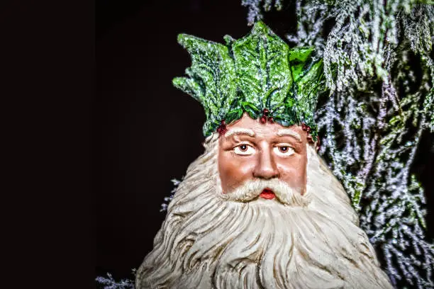 Father Christmas - The Holly King - Ceramic Christmas tree decoration with sparkly bokeh greenery background- room for copy.