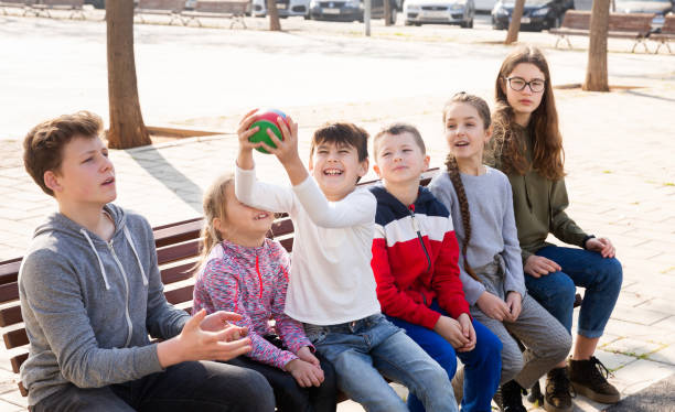 istock Children sitting on bench and playing ball 1351310521