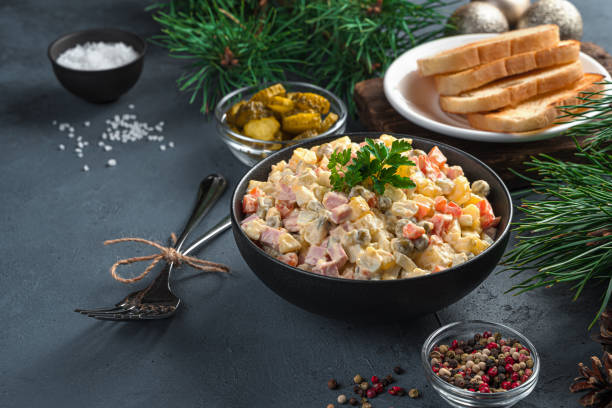 istock Olivier salad in a black bowl on a dark background with pine branches 1351311735
