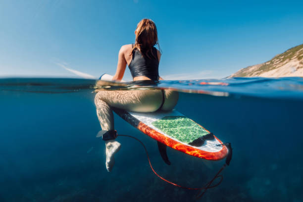 istock Sexy surf girl on surfboard in blue ocean, split view 1351312066