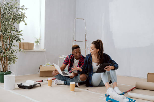 istock Interior designers construction managers architects work in newly constructed apartment building apartment renovation young woman and co-worker sit on floor with mugs of coffee laptop tablet plan 1351314040