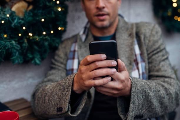 foto de cerca de manos de hombre usando un teléfono móvil en un café al aire libre - people winter urban scene chair fotografías e imágenes de stock