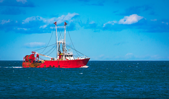 A red fishing trawler sets out for a fishing trip in Cape cod Bay and beyond.