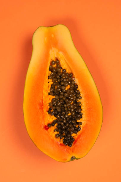 istock Papaya fruit on a orange background. Half papaya. 1351317962