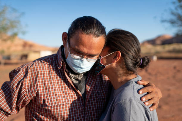 Navajo couple embracing and wearing Covid-19 coronavirus masks in Monument Valley Tribal Park at the Arizona/Utah border Navajo couple embracing and wearing Covid-19 coronavirus masks in Monument Valley Tribal Park at the Arizona/Utah border navajo nation covid stock pictures, royalty-free photos & images