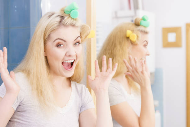 istock Blonde woman using hair rollers 1351318984