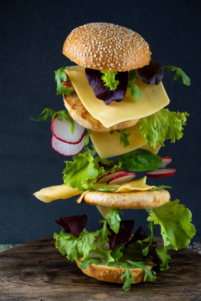 istock Hamburger bun, double chicken cutlet with cheese, lettuce, arugula and radish. Meat, vegetables and bread. Ingredients. Homemade burger on a plate. Table made of colored tiles 1351320653