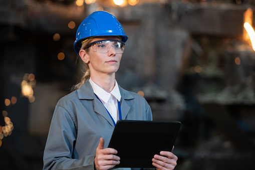 Female engineer with digital tablet in foundry. Production factory, metal industry, engineering and people at work concept.