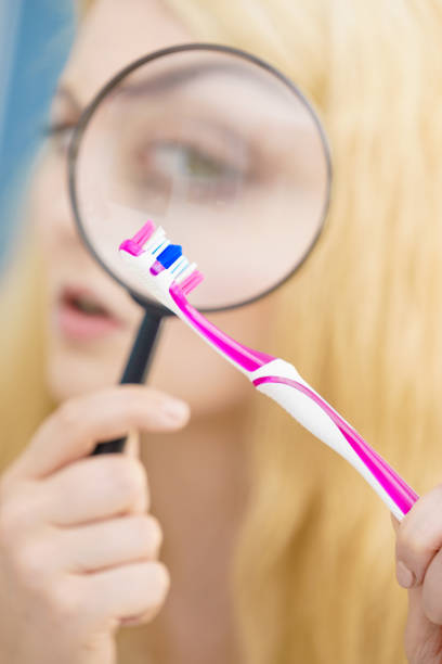 istock Woman looking at toothbrush through loupe 1351321031