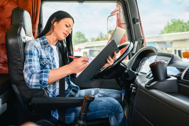 istock Female truck driver using a mobile app and writing on a clipboard 1351322384