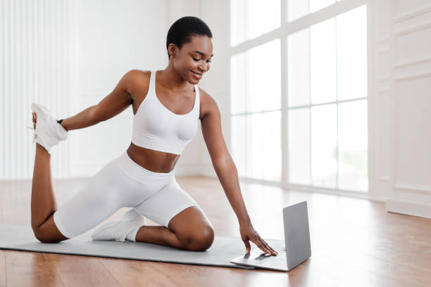 istock Cheerful black woman stretching leg muscles using personal computer 1351323785