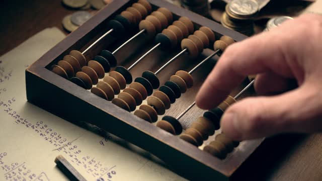 Male hand counting money using old wooden abacus close up
