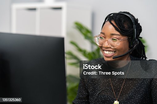 istock Customer service agent, financial advisor call center employee sits at desk in company in front of computer screen, headphones with microphone on ears, connecting with caller, solving problem 1351325360