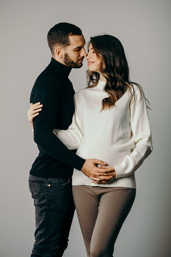 Beautiful couple posing in studio. She is pregnant in last trimester and looks amazing.