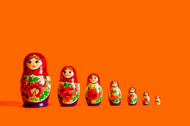 las muñecas de anidación familiar en fila se paran sobre un fondo naranja. aislar - russian nesting doll doll russian culture nobody fotografías e imágenes de stock