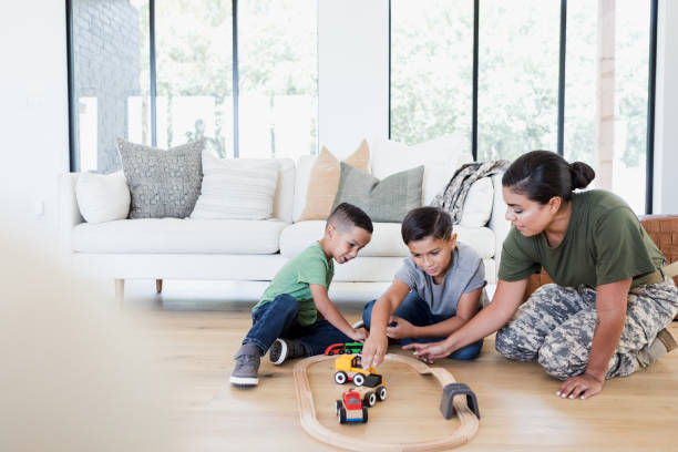 After work, soldier mom plays with sons in living room Before changing out of her uniform after work, the mid adult soldier mom takes time to play with her sons on the floor of their home. military lifestyle stock pictures, royalty-free photos & images