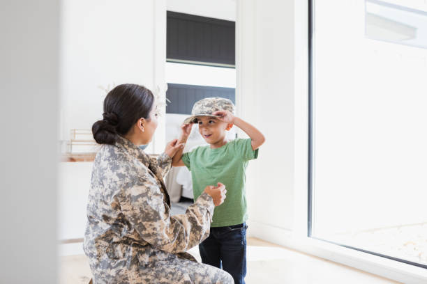 istock Young son tries on mother's army uniform cap 1351328645