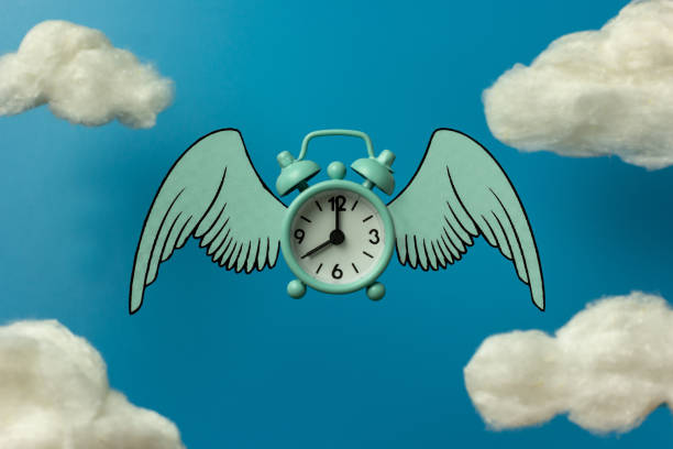 istock Flying blue alarm clock and white clouds on a blue background. 1351330775