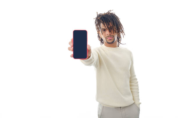 Serious man showing blank screen mobile phone to camera while standing on isolated background. Advertising and promotion concept.
