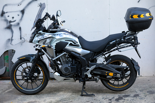 Side view of silver colored Honda enduro motorbike with box