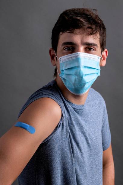 istock Young man posing showing his vaccination band-aid in his arm 1351333819