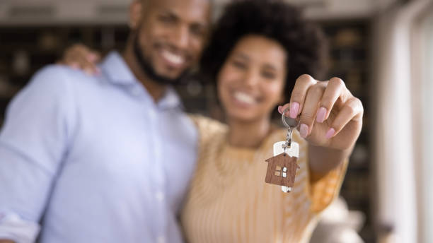 Close up keys in hands of blurred african couple. Close up focus on keys in hands of blurred joyful young loving african american married couple. Sincere mixed race homeowners celebrating purchasing own flat, feeling excited of renting new dwelling. moving house stock pictures, royalty-free photos & images