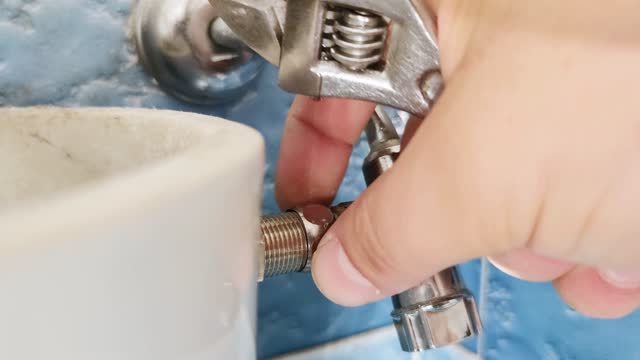 A plumber installs water heater hose.