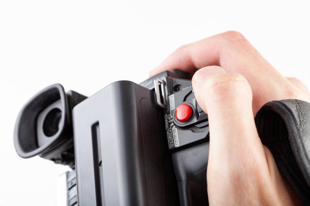 istock Handheld camcorder, old retro video camera object held in hand, closeup, white background, cut out. Finger on the red rec record button. Filmmaking, movie making abstract concept, first person pov 1351335086