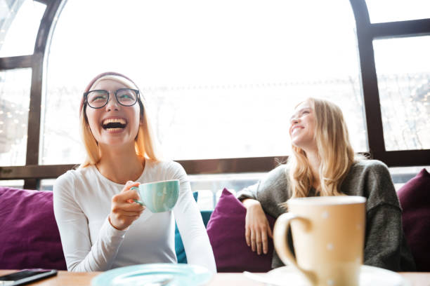 istock Two happy women drinking coffee and laughing in cafe 1351335405
