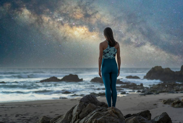 istock unknown woman standing on the beach with Milky Way background, back view 1351336591