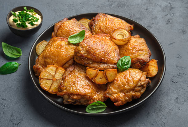 istock Fried chicken thighs with fresh basil, onion and sauce on a dark background 1351337708