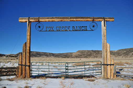 Antonito, Conejos County, San Luis Valley, Colorado, USA: ranch entrance gate - Fox Creek ranch with snow and hills in the background - quintessential Americana - the West.