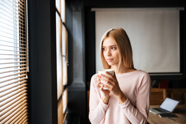 istock Beautiful young woman standing in cafe drinking coffee 1351338855