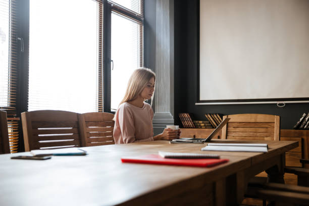 istock Happy young woman drinking coffee while work with laptop 1351339815