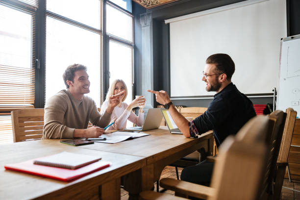 istock Smiling colleagues sitting near coffee while work with laptops 1351340166