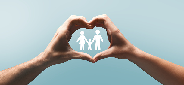 Hands of european man and lady make heart gesture with silhouette of mom, dad and kid between arms, on blue background, panorama. Care for family, love, relationship, marriage, protect due covid-19