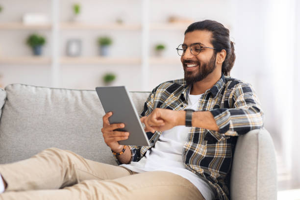 istock Relaxed indian man chilling at home with digital tablet 1351341364