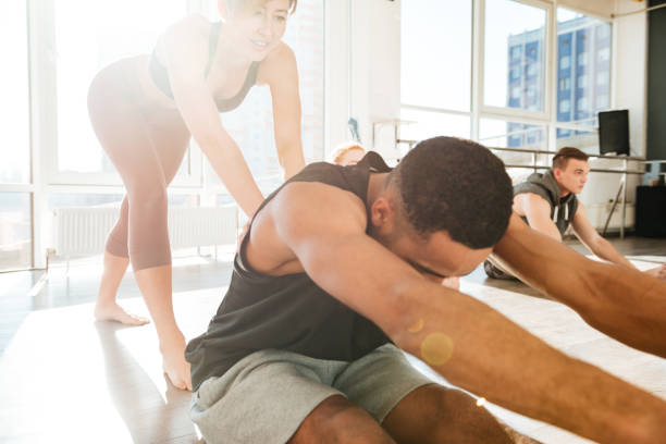 istock Man stretching and working out with trainer in yoga studio 1351342208