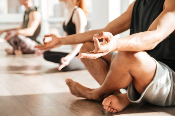 istock Man sitting and meditating in lotus pose with group 1351342275