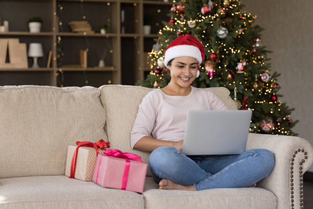 istock Smiling young beautiful Indian woman using computer, celebrating Christmas. 1351343453