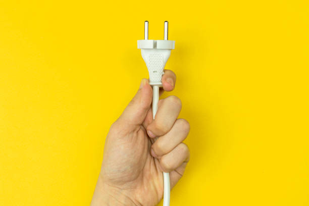 istock Hand with electrical power cable. Yellow background, flat lay, top view and copy space photo 1351344713